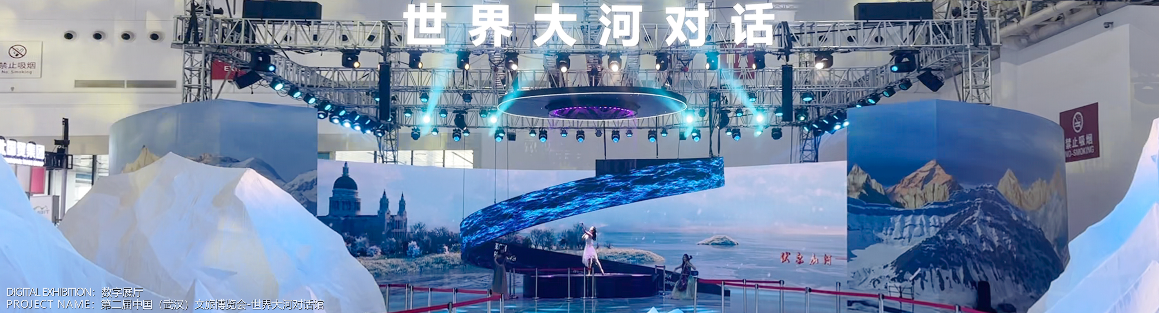 数字空间主视觉 02：展馆现场的冰雪主题舞台与螺旋屏幕，顶部悬挂世界大河对话字样，底部标注数字展厅·第二届中国（武汉）文旅博览会世界大河对话馆